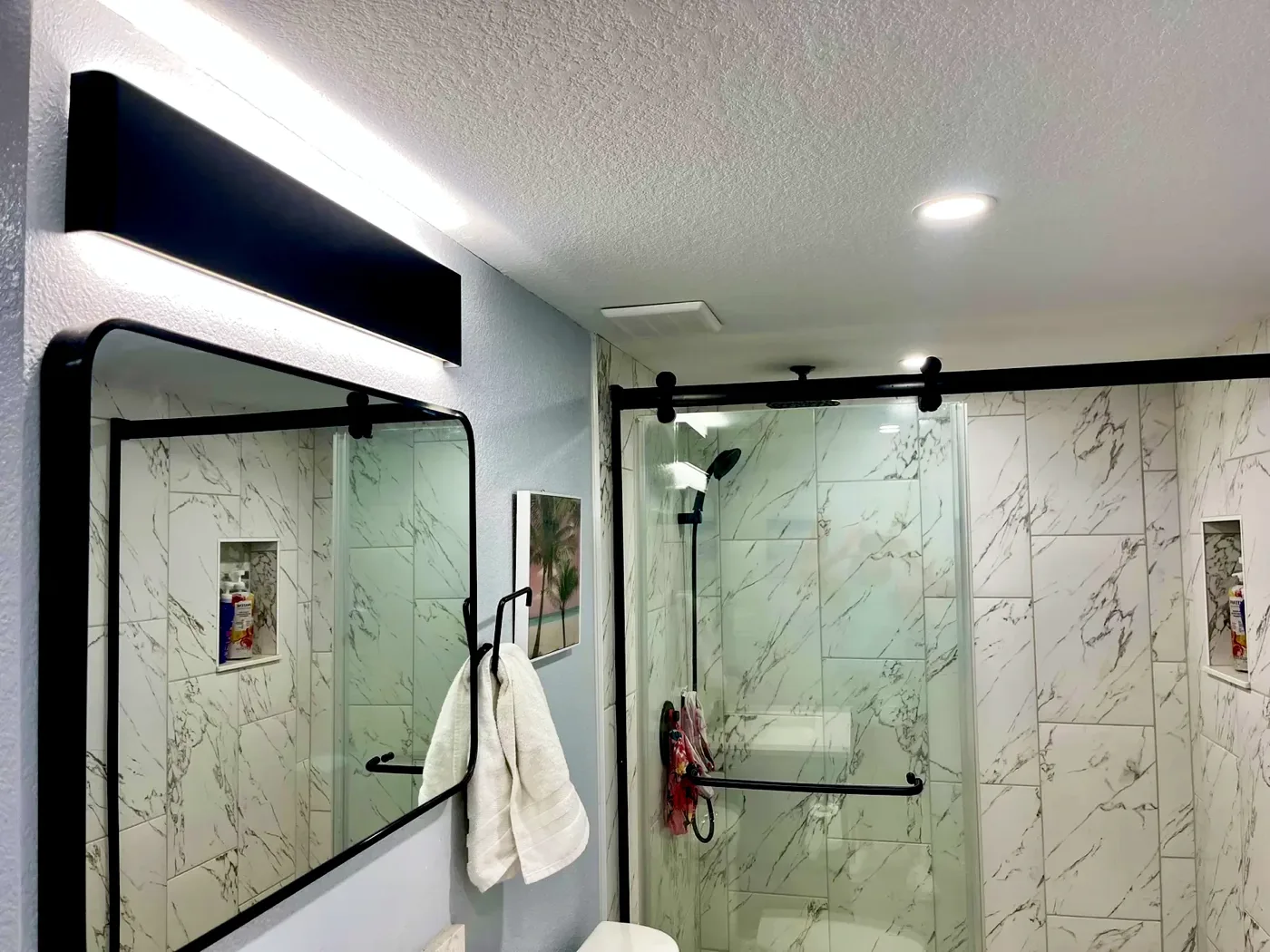 Basement bathroom with a linear vanity light and glass shower