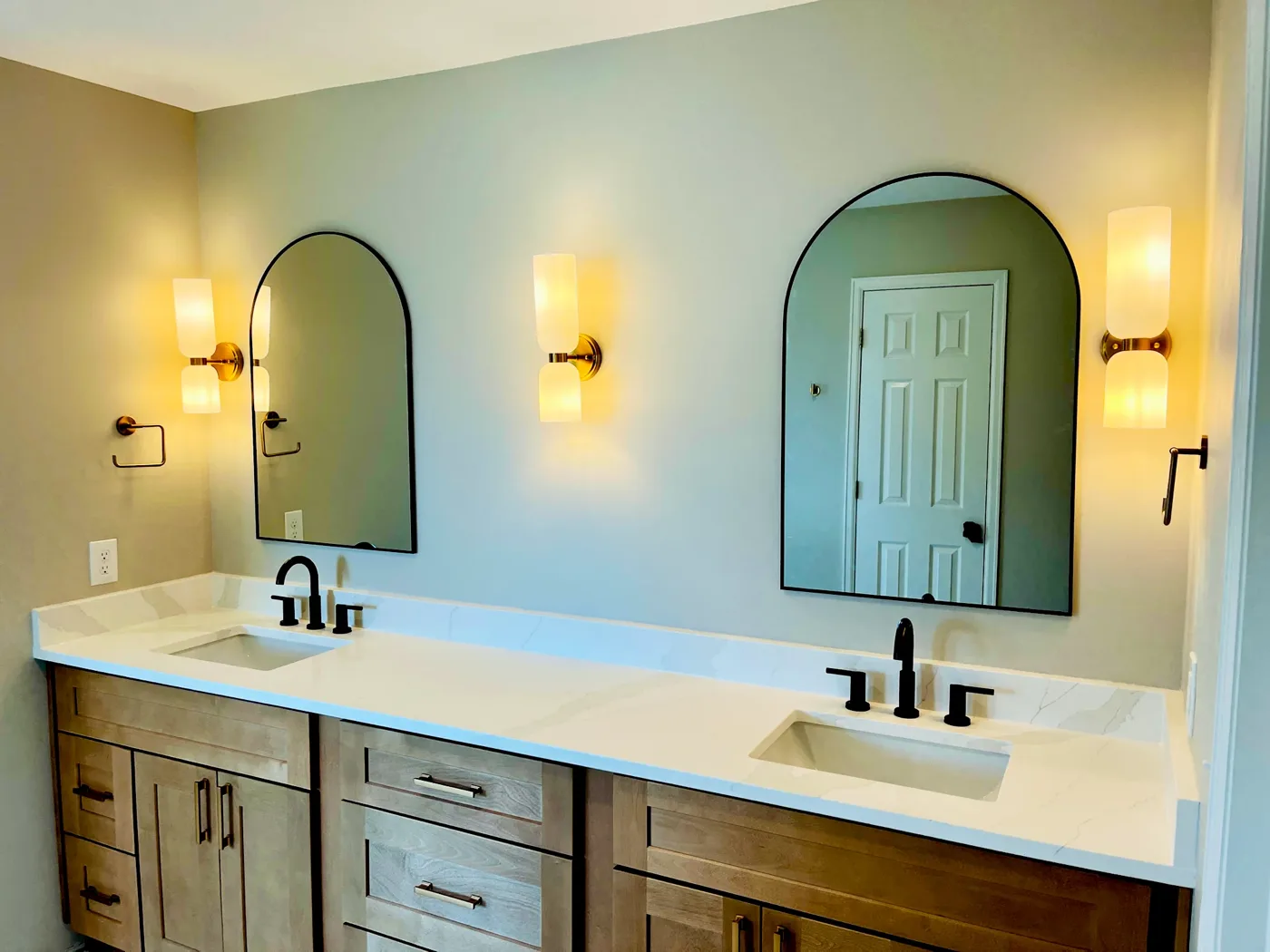 Double vanity from the doorway, sconces lit