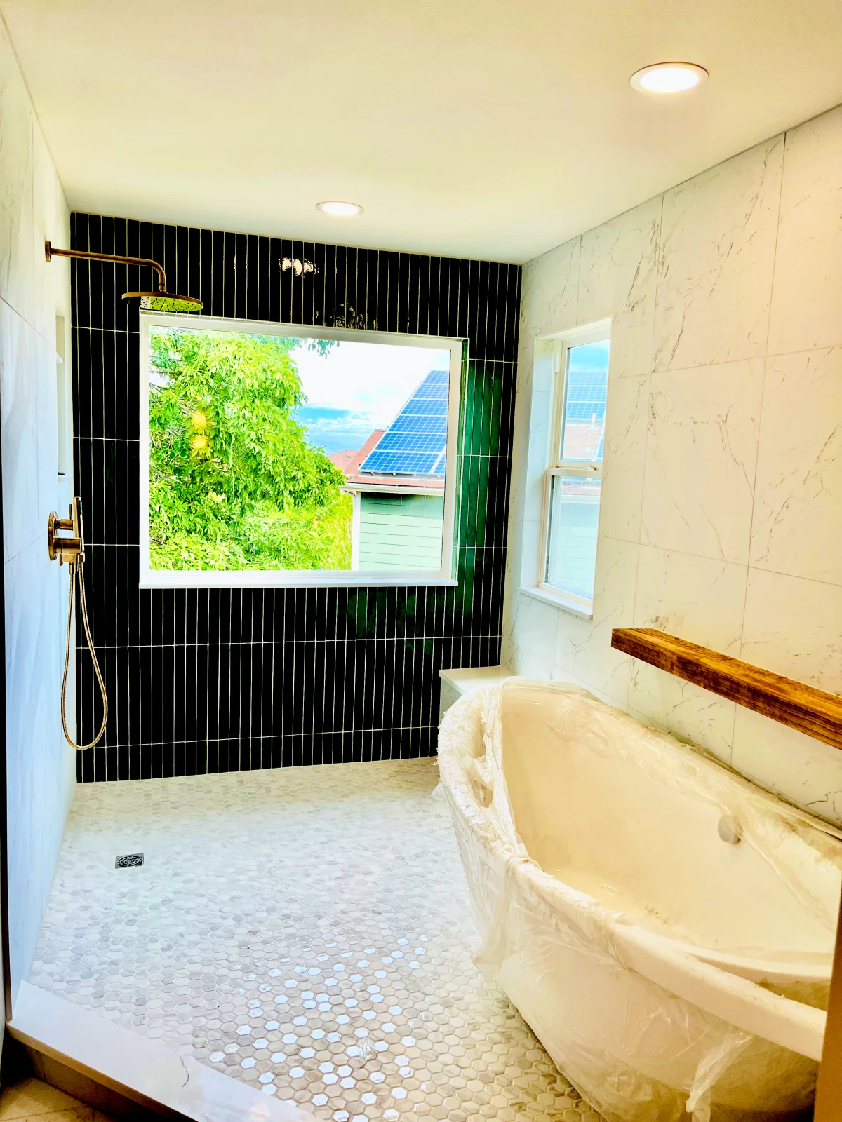 Walk-in shower with green tile, freestanding tub, and recessed lighting
