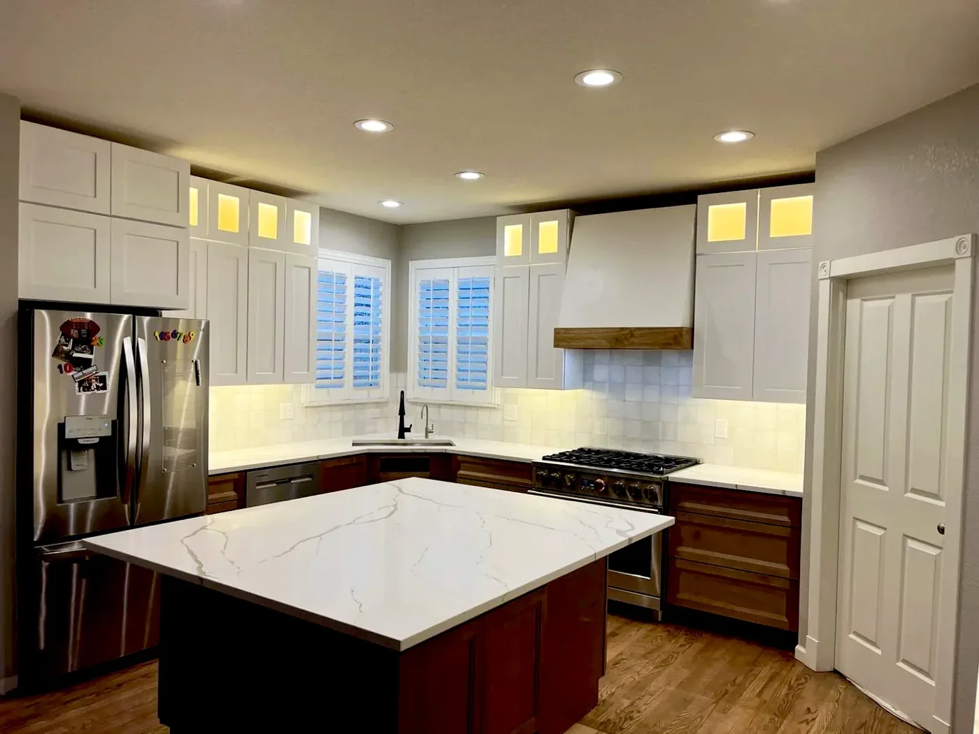 White kitchen with cabinet uplights and recessed lighting