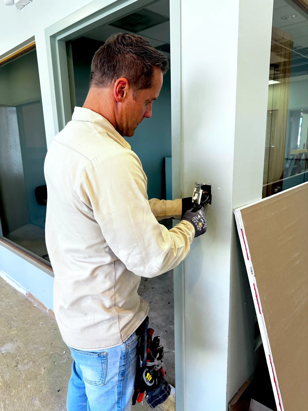 Electrician installing a wall device during an office build-out