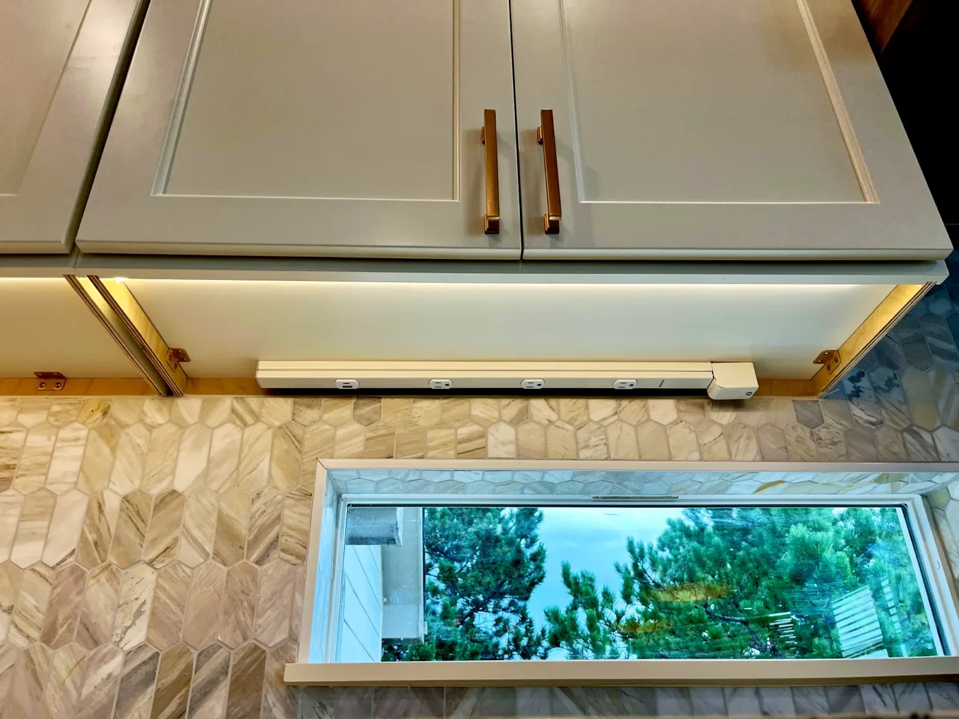Under-cabinet LED strip lighting above a marble backsplash